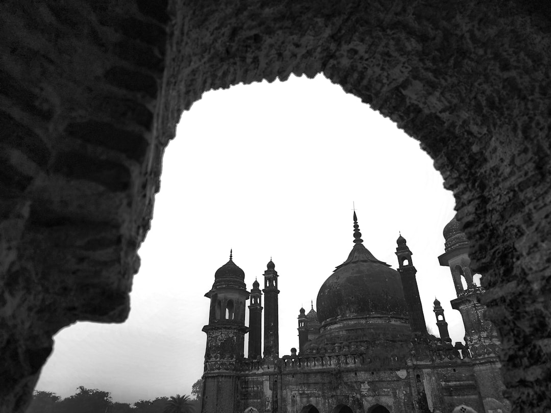 a black and white photo of an old building, a conjuring sight of history and mystery.