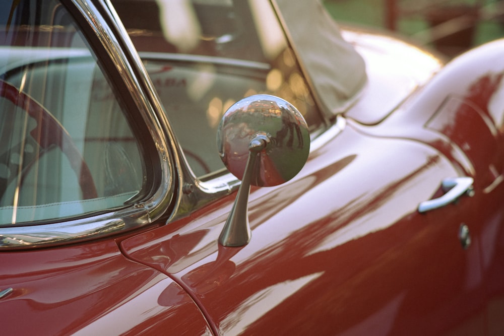 a close up of the side mirror of a red car