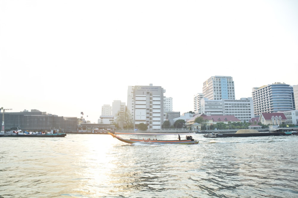 a boat traveling down a river next to tall buildings