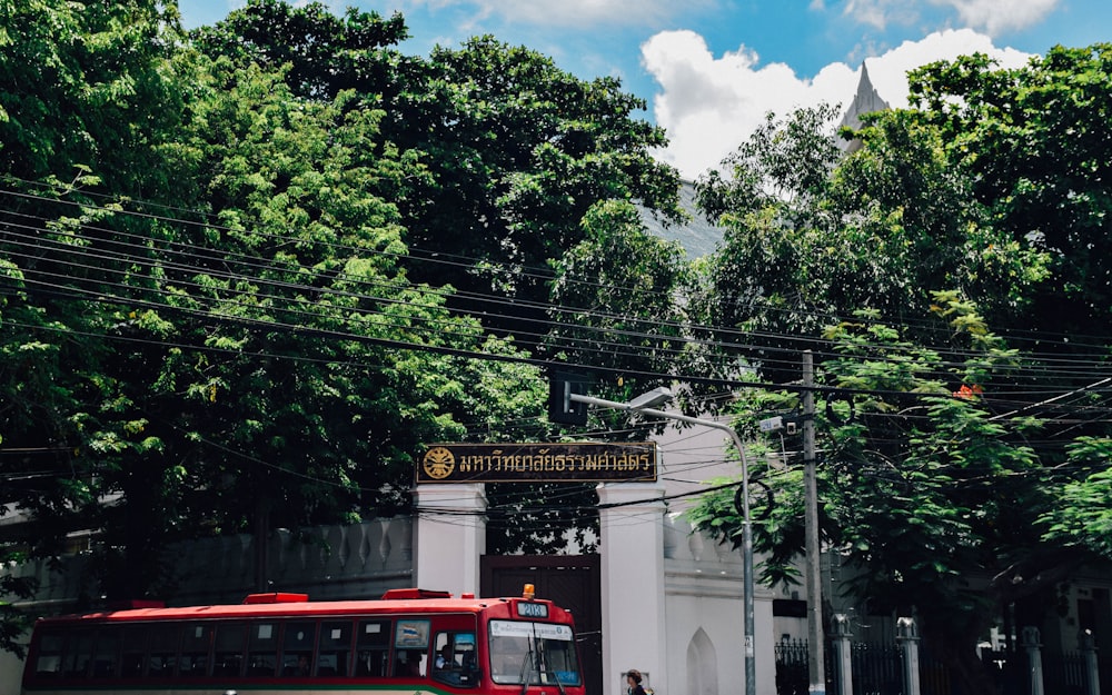 a red bus driving down a street next to a tall white building