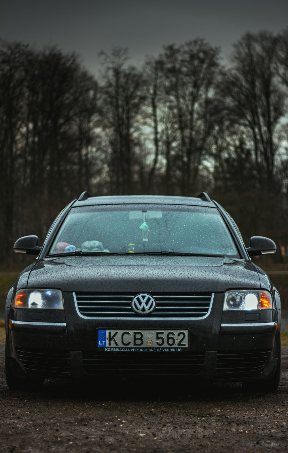 a black car parked in front of some trees