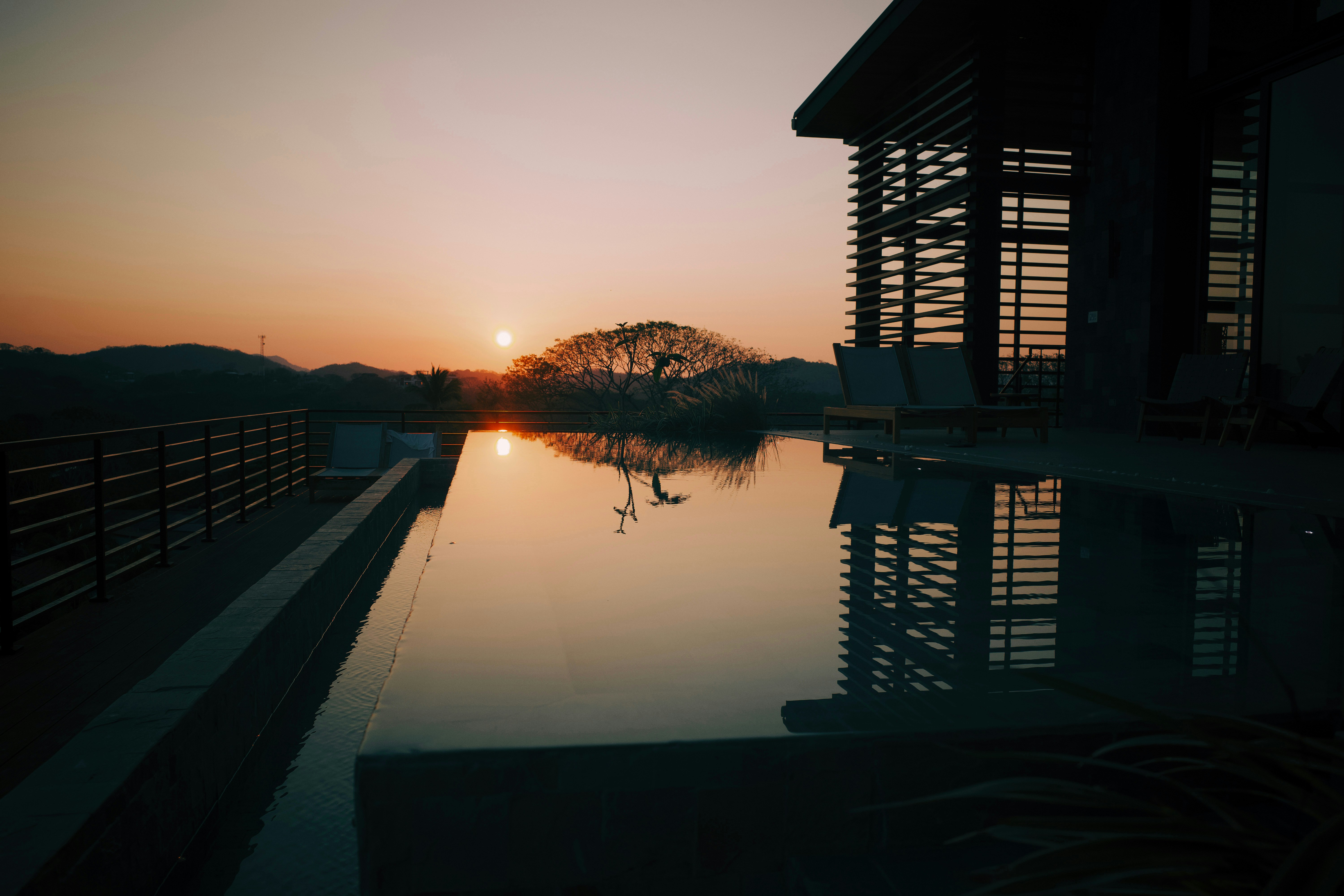 the sun is setting over a body of water, Sunrise, infinity pool, pool, architecture, airbnb, tree, reflection, tamarindo, costa rica
