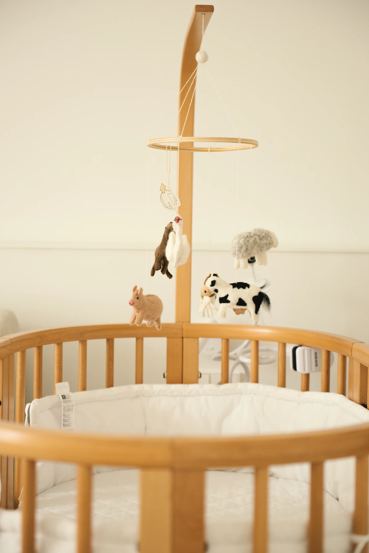 Wooden crib with soft mobile and neutral nursery bedding