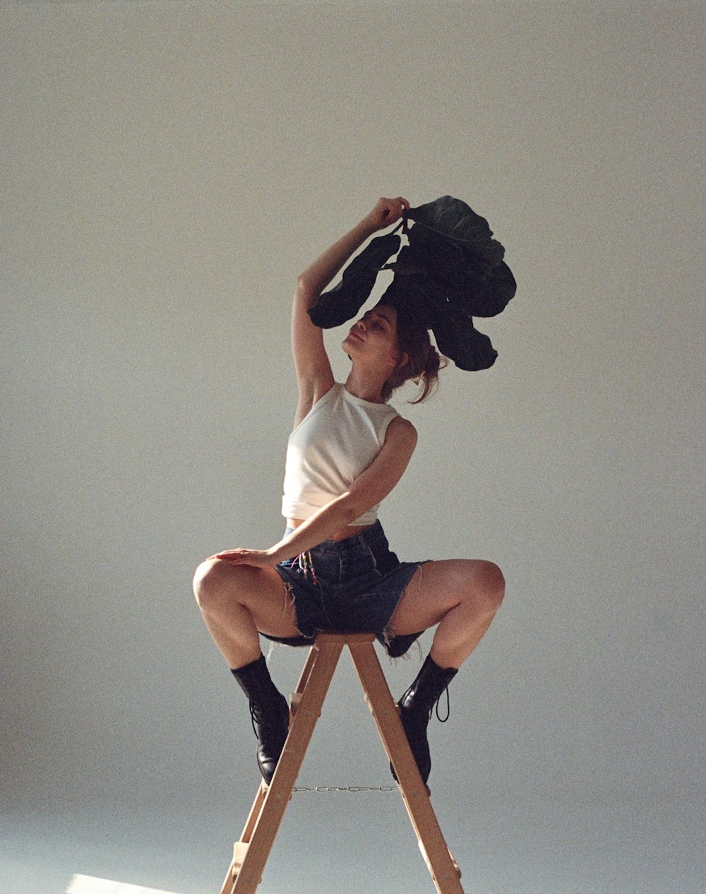 a woman sitting on top of a wooden ladder