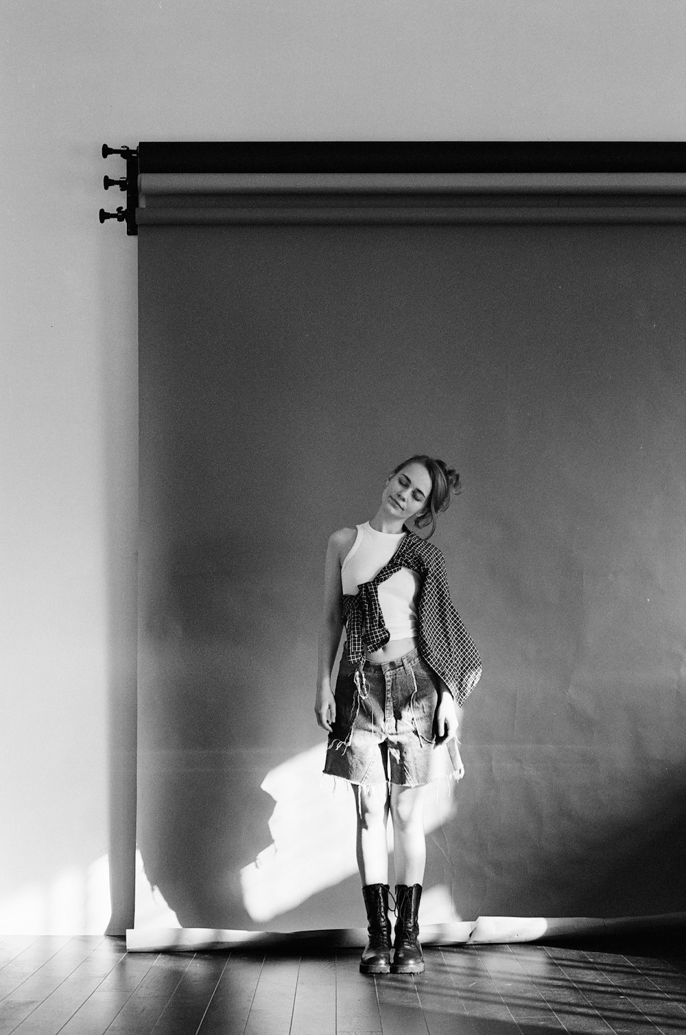 a black and white photo of a woman standing in front of a wall