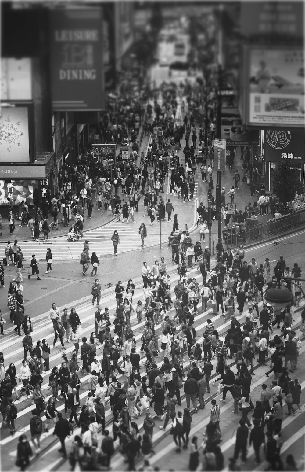 a black and white photo of a crowd of people crossing a street