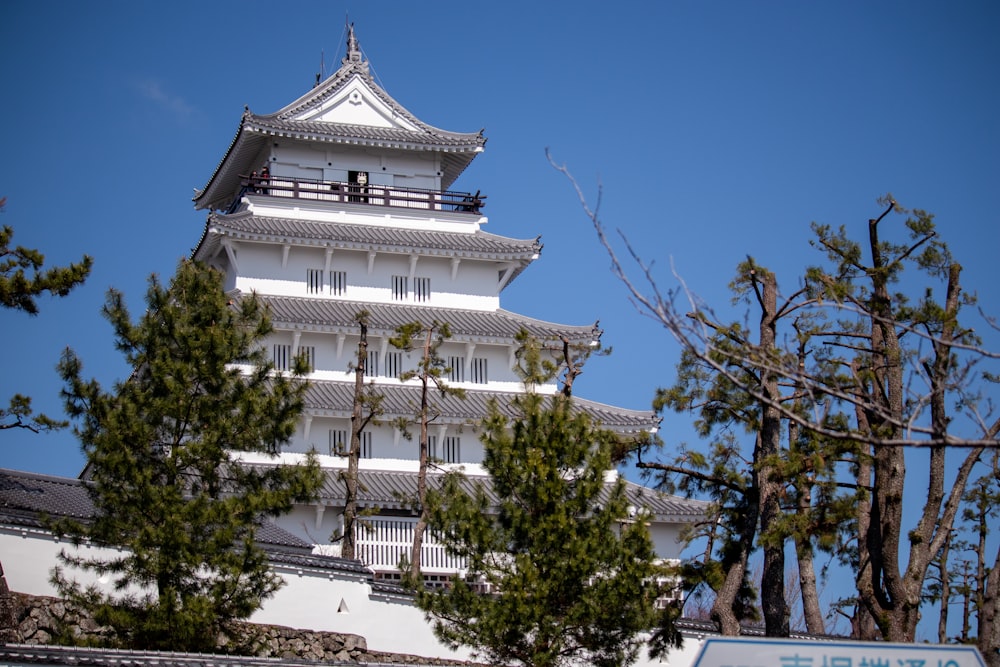 a tall white building sitting next to a forest