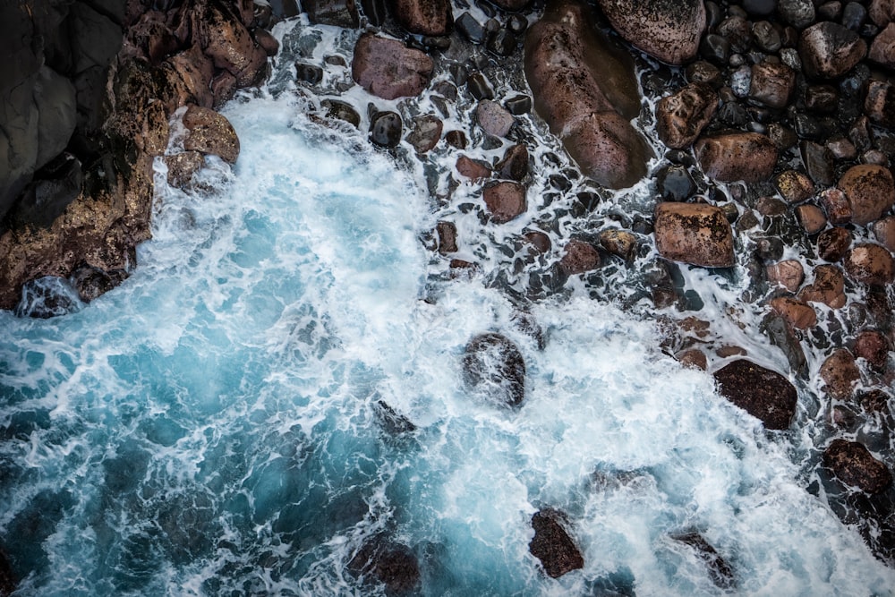 an aerial view of the ocean and rocks