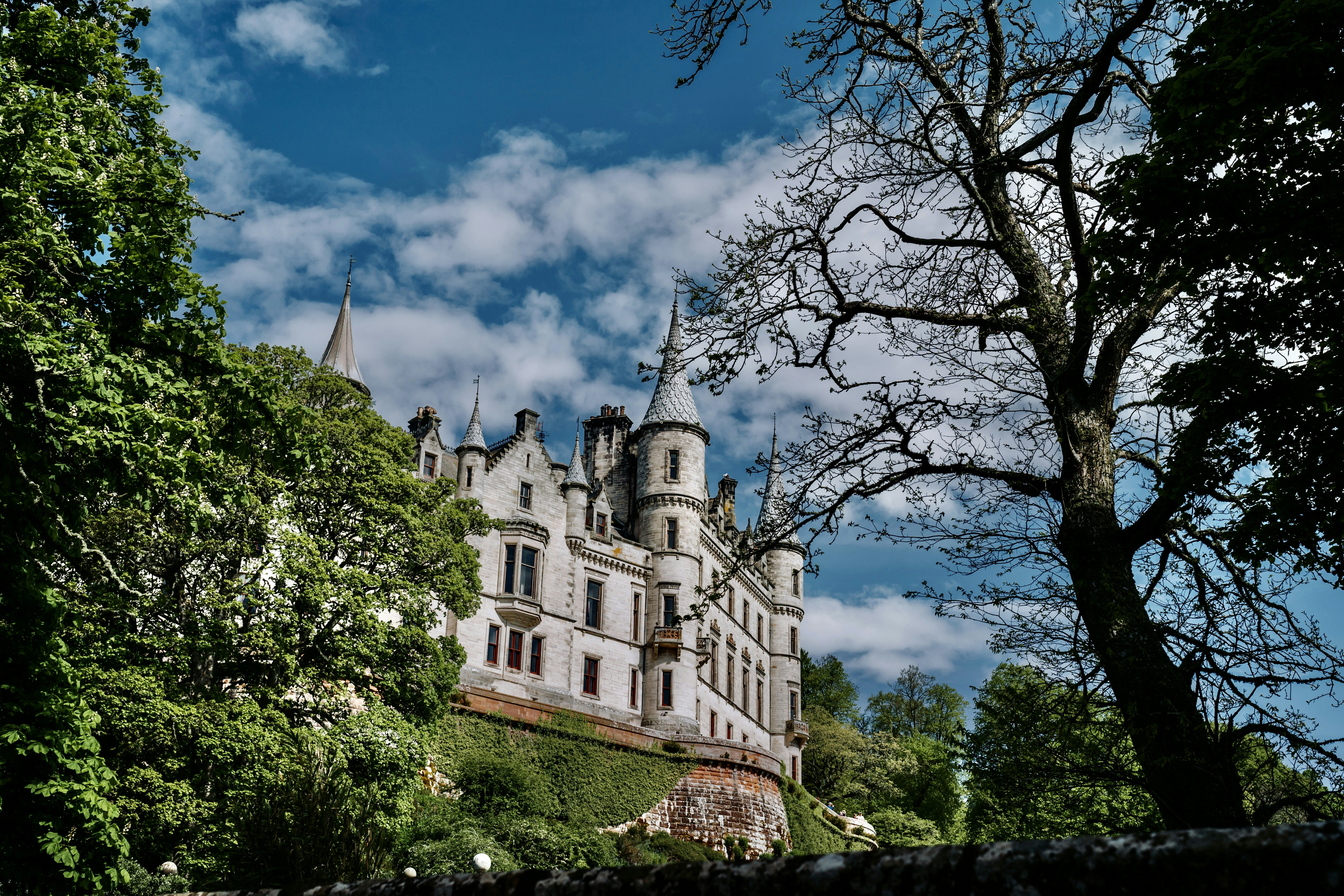 a large castle sitting on top of a lush green hillside, 