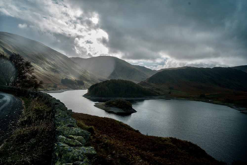 a body of water surrounded by mountains under a cloudy sky