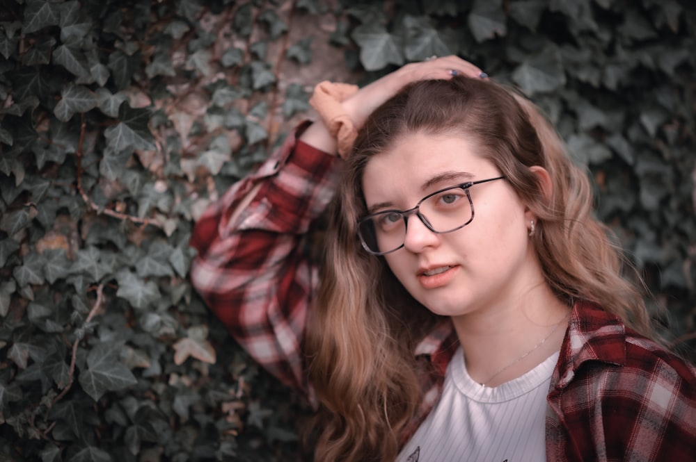 a girl wearing glasses standing in front of a tree