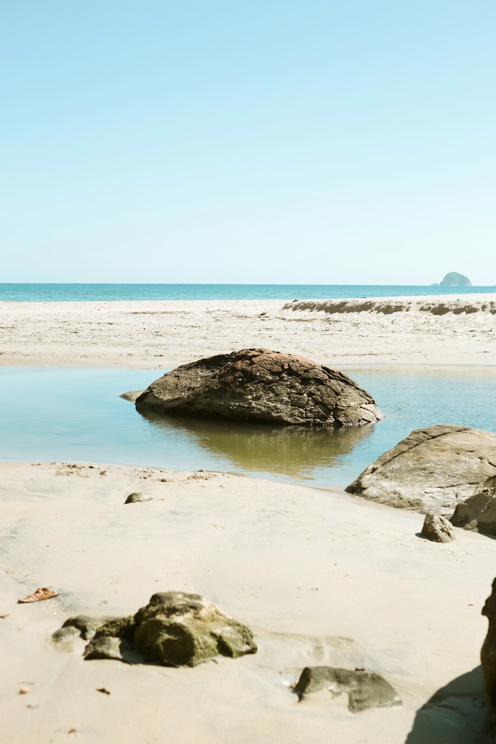 a large rock sitting on top of a sandy beach