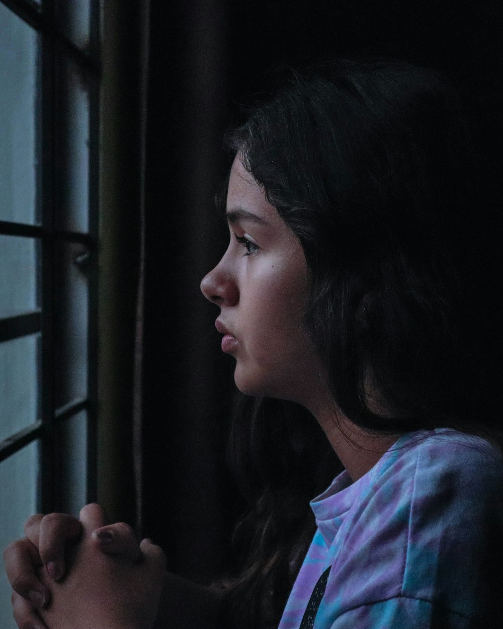 a young girl looking out a window at night