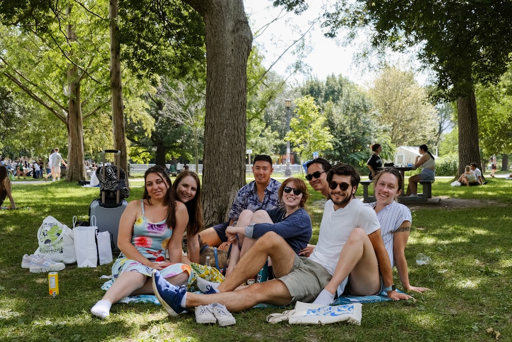 a group of people sitting on top of a lush green park