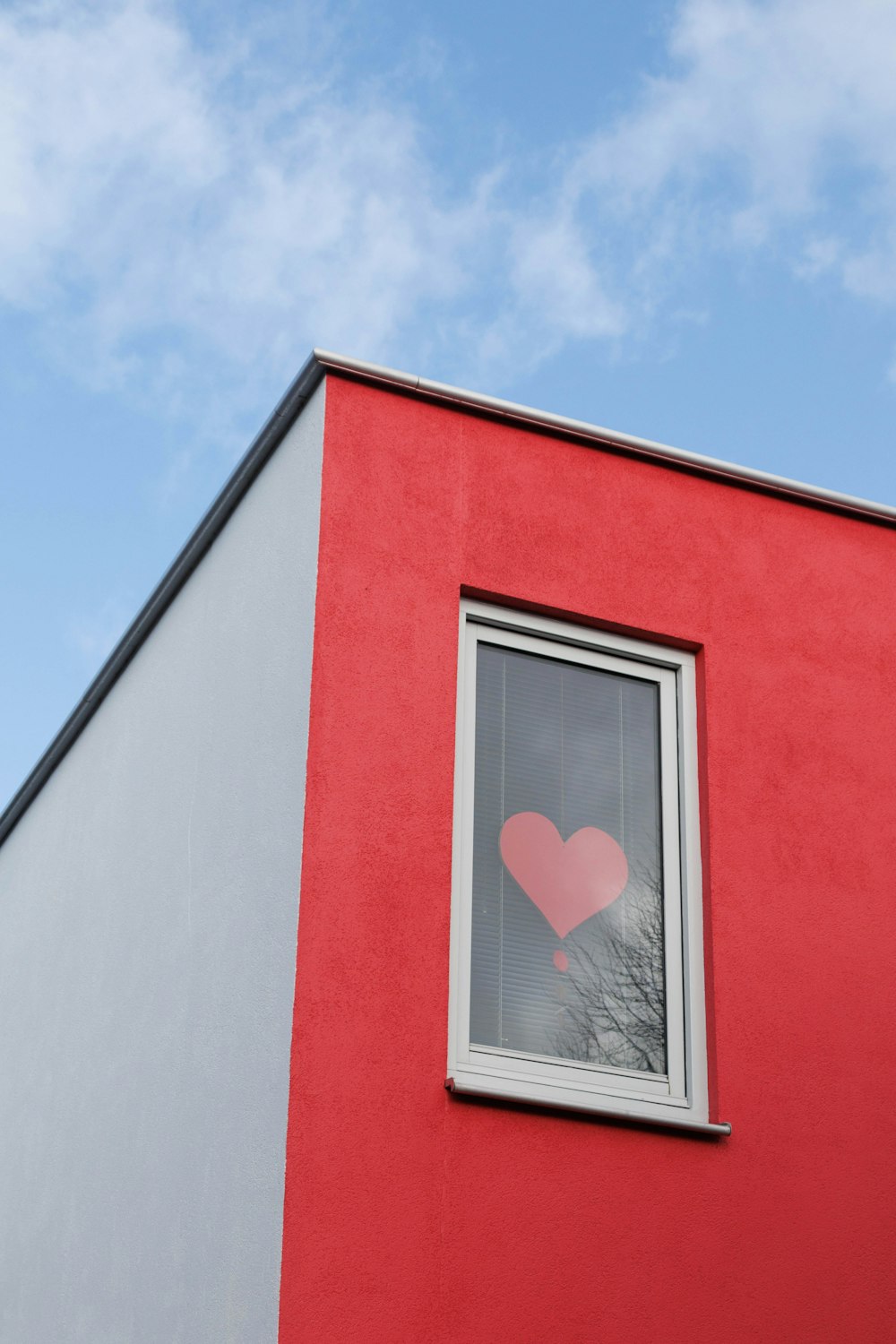 a red and gray building with a window with a heart drawn on it