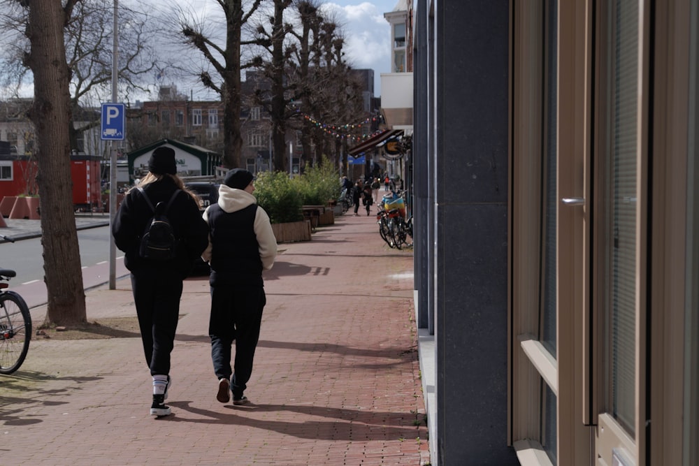 a couple of people walking down a sidewalk