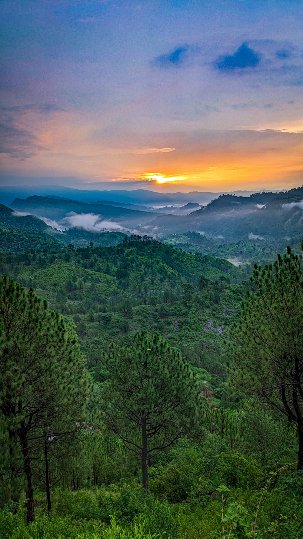 In der Ferne geht die Sonne über den Bergen unter