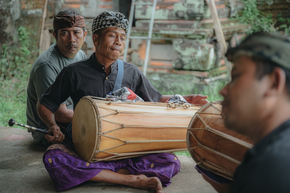 a group of men sitting on the ground playing musical instruments