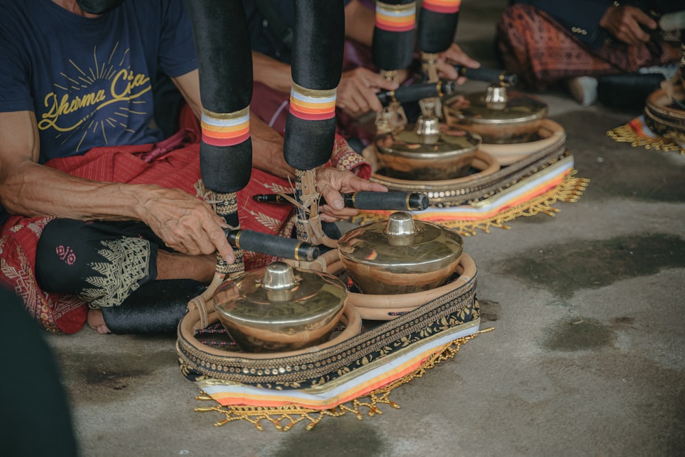 a group of people sitting on the ground with bells