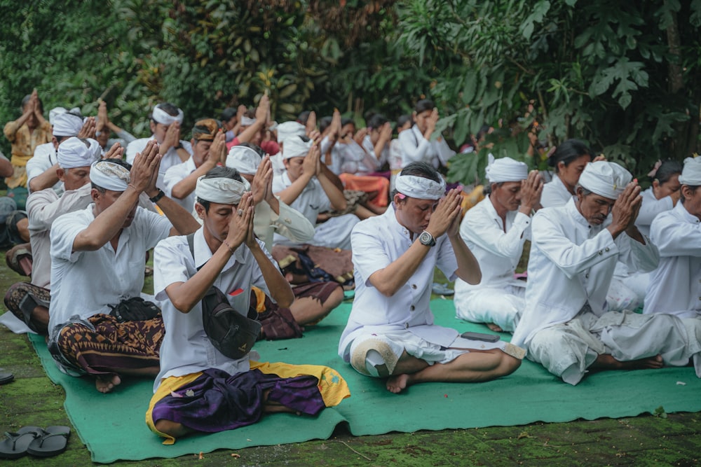 a group of people sitting on top of a green mat