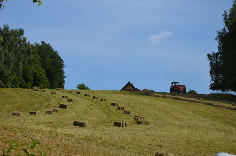 a field with hay bales in the foreground and a tractor in the background