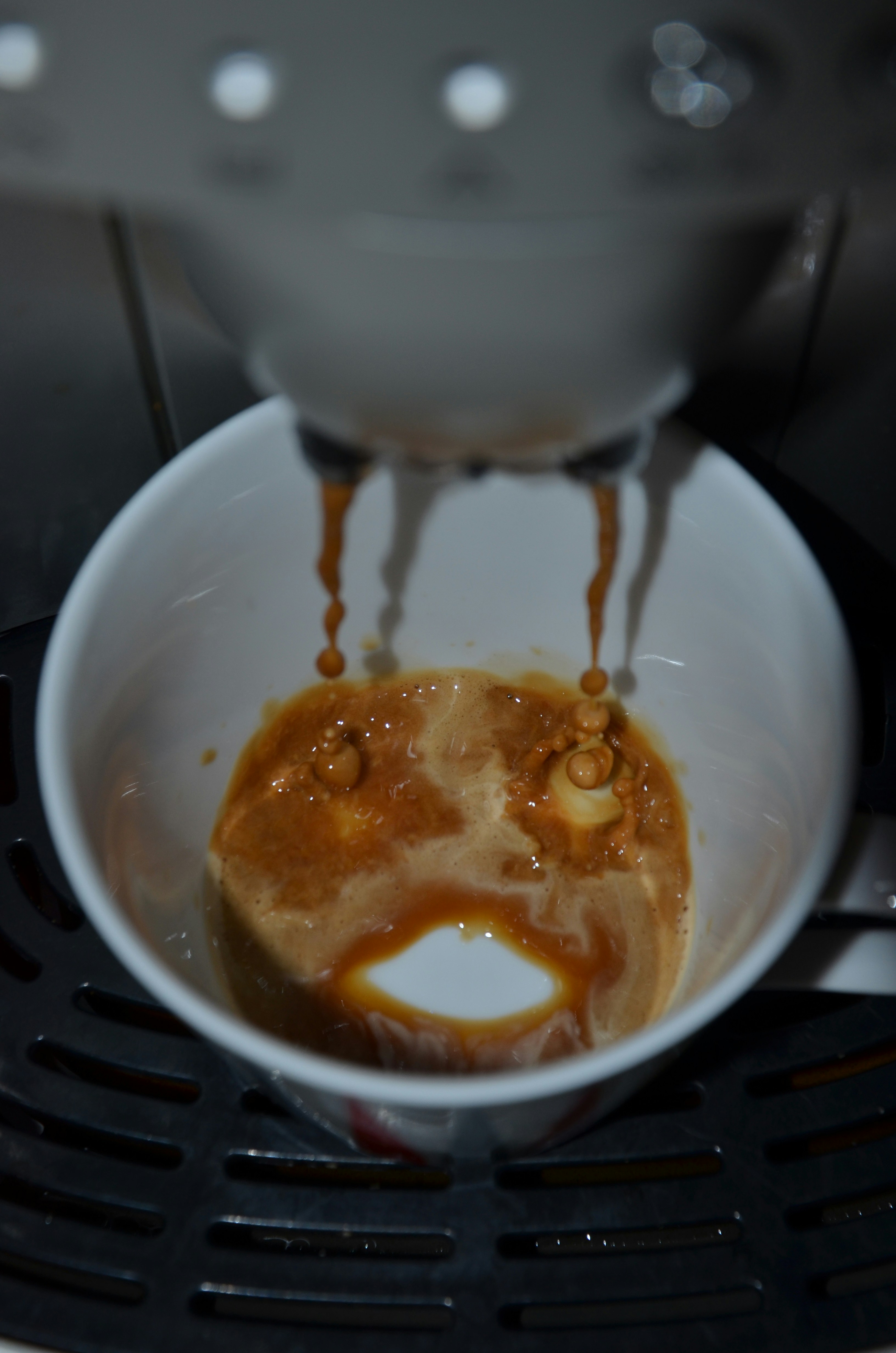 Espresso being poured into a white ceramic cup, moody dark background, high contrast black and white