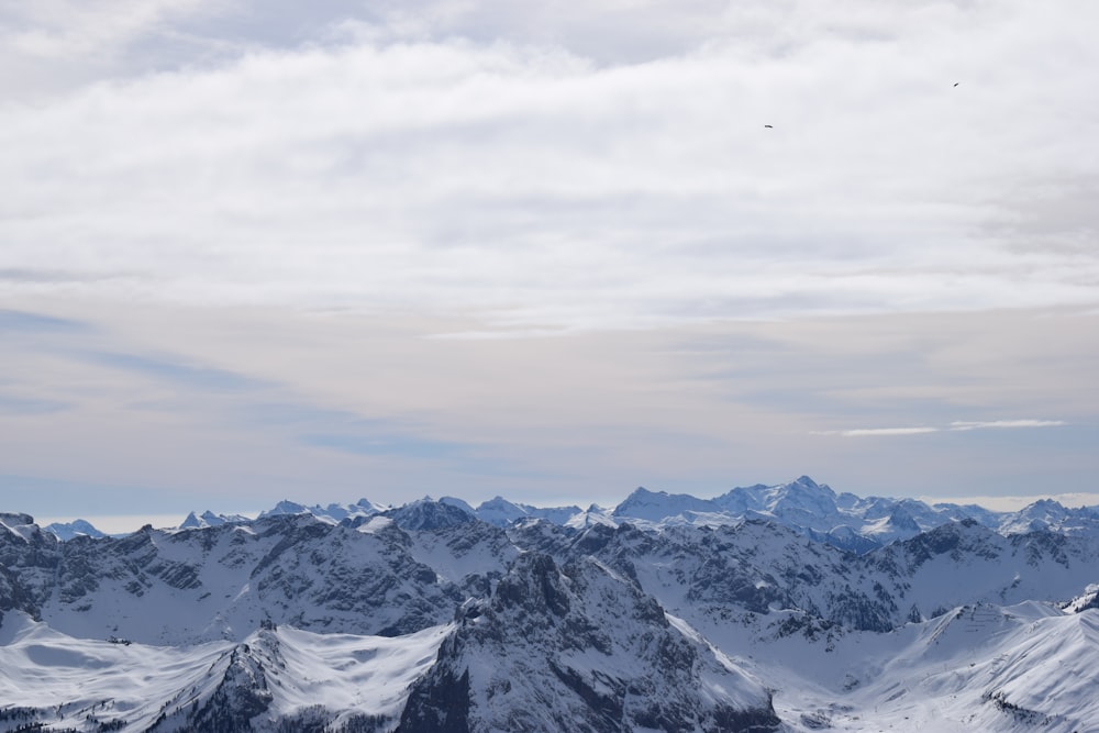 a group of mountains covered in snow under a cloudy sky