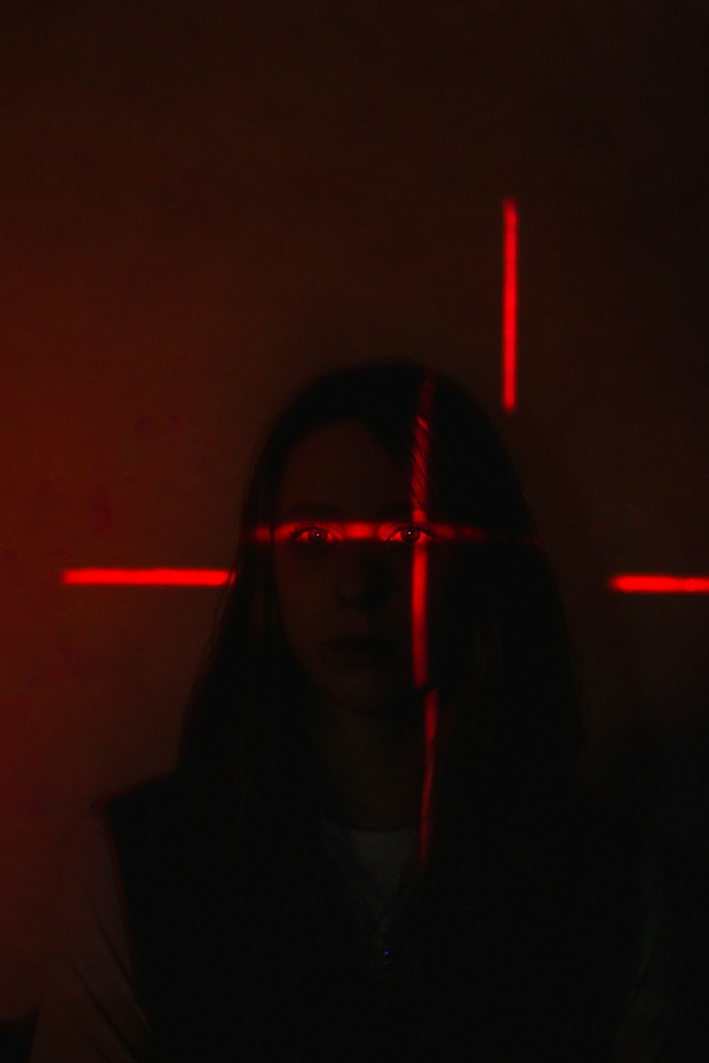 a woman standing in a dark room with a cross on the wall