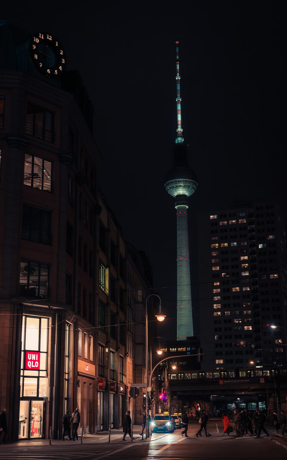 a city street at night with a tall building in the background