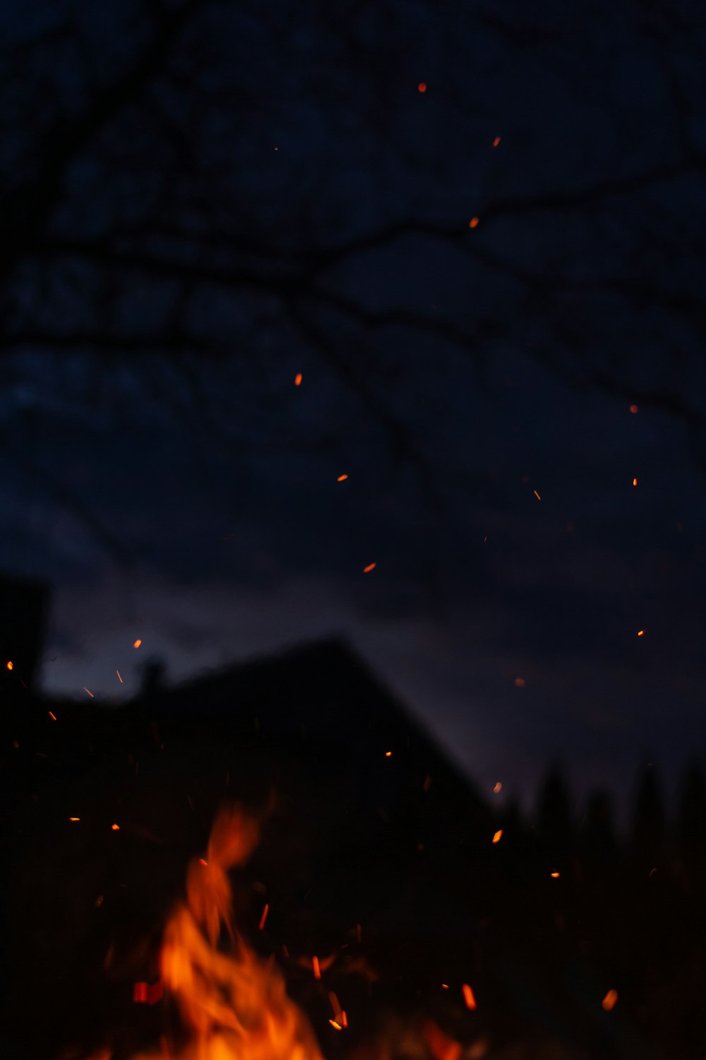 a fire burning in the dark with a house in the background