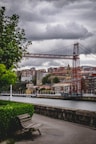 a wooden bench sitting next to a river under a cloudy sky