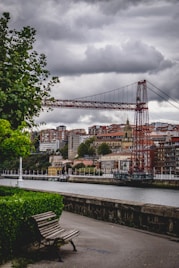 a wooden bench sitting next to a river under a cloudy sky