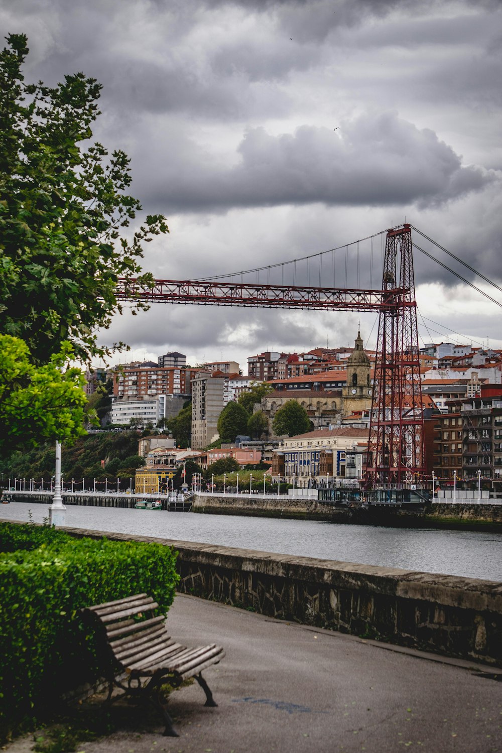 a wooden bench sitting next to a river under a cloudy sky