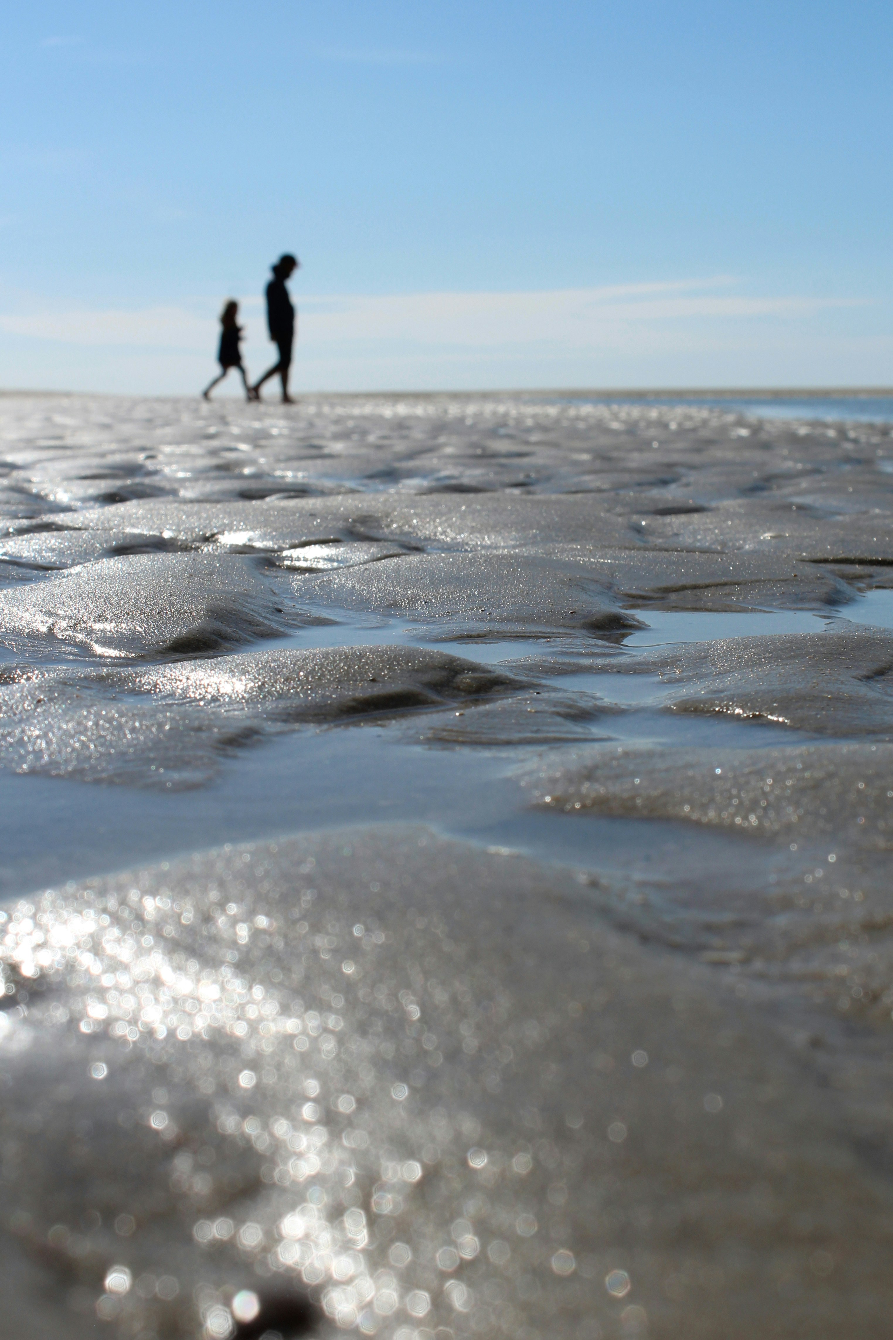 Un par de personas caminando por una playa de arena