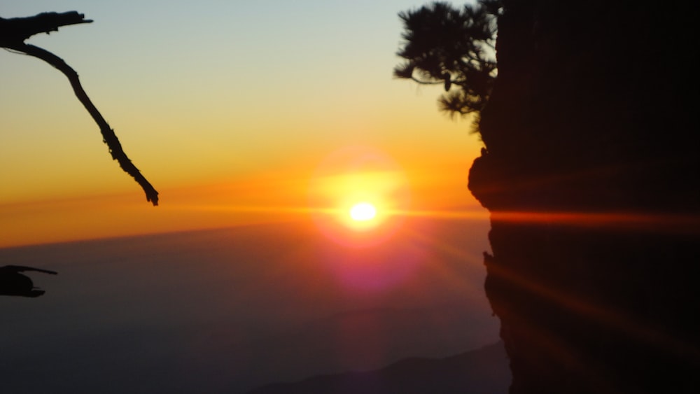 the sun is setting over the horizon of a cliff