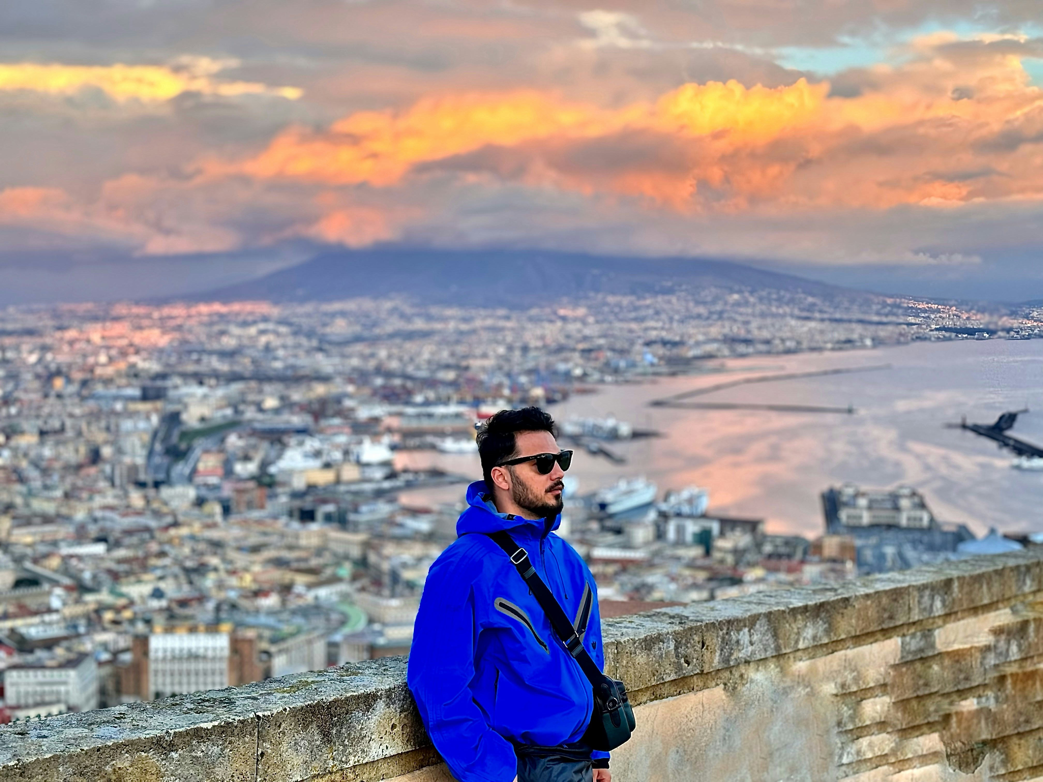 a man in a blue jacket is standing on a wall