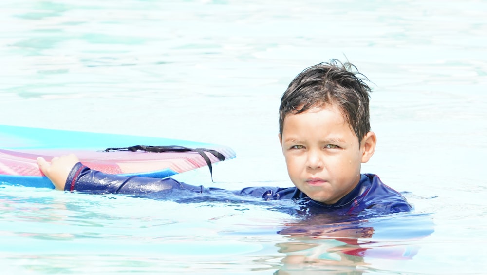 a young boy in the water with a surfboard