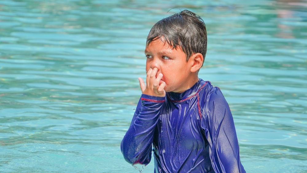 a young boy in a wet suit standing in the water