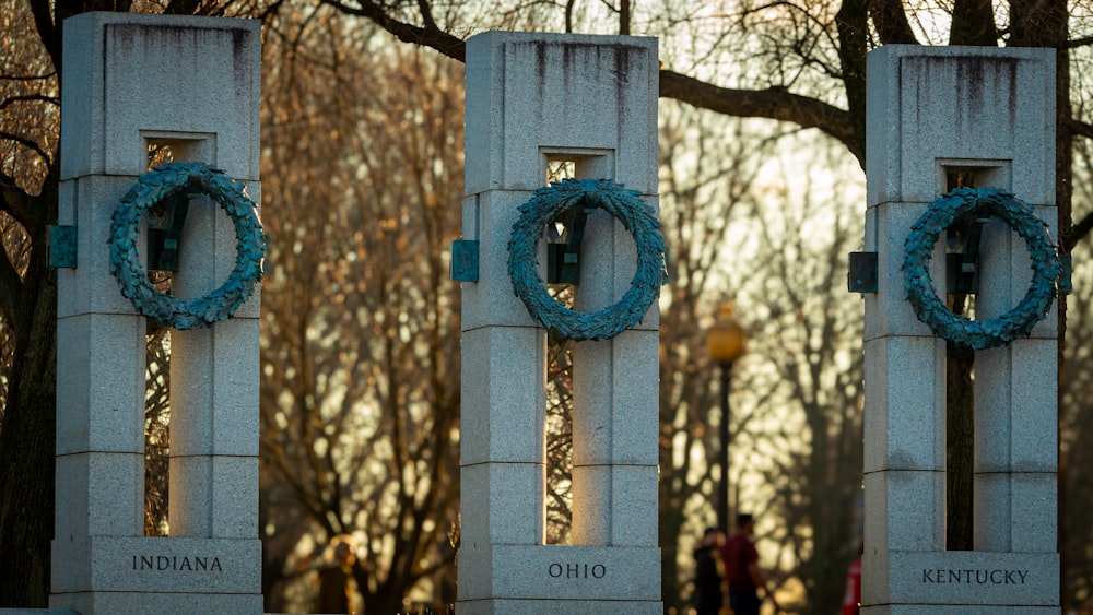 a couple of white pillars with wreaths on them