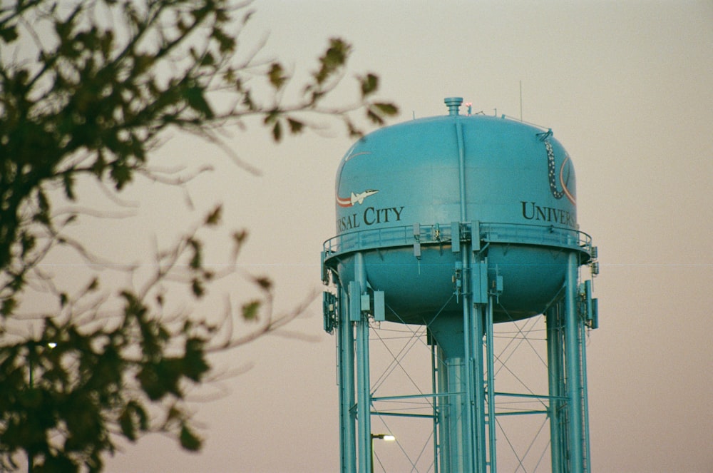 a large blue water tower sitting next to a tree