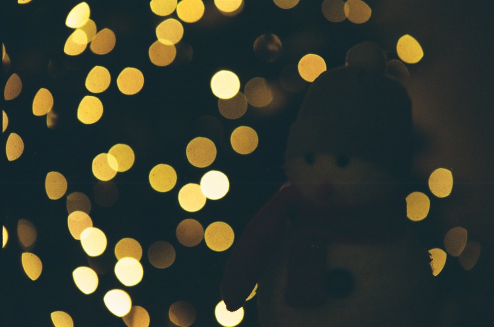 Un osito de peluche que está sentado frente a un árbol de Navidad