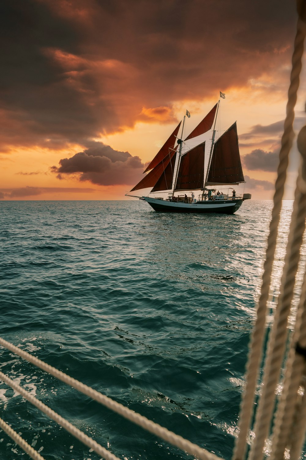 um veleiro navegando no oceano ao pôr do sol