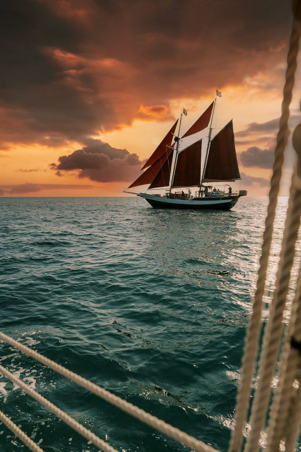 a sailboat sailing in the ocean at sunset