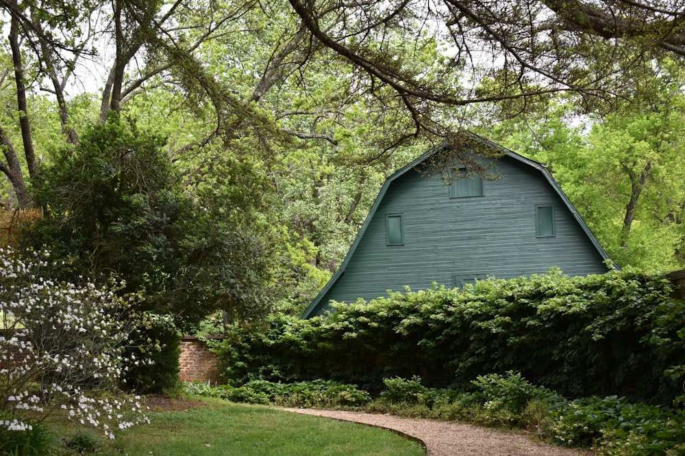 a green barn surrounded by trees and bushes
