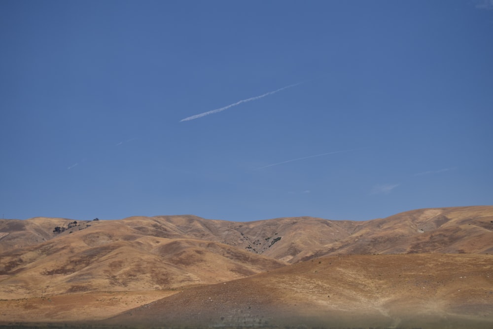 a plane flying over a mountain range under a blue sky