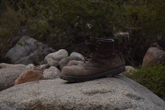a pair of brown boots sitting on top of a rock
