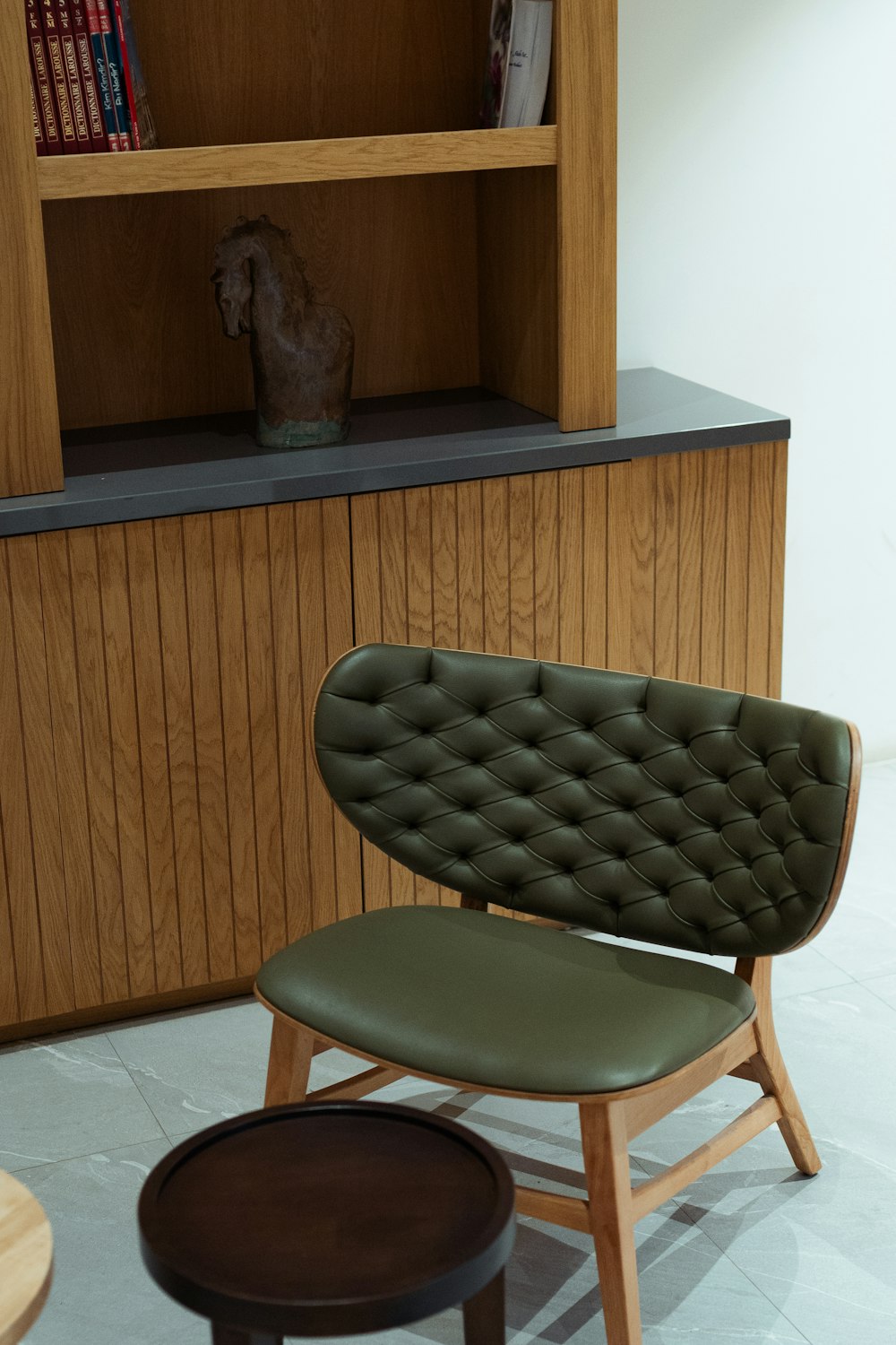 a green chair sitting in front of a book shelf