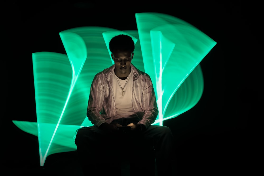 a man sitting in front of a green light