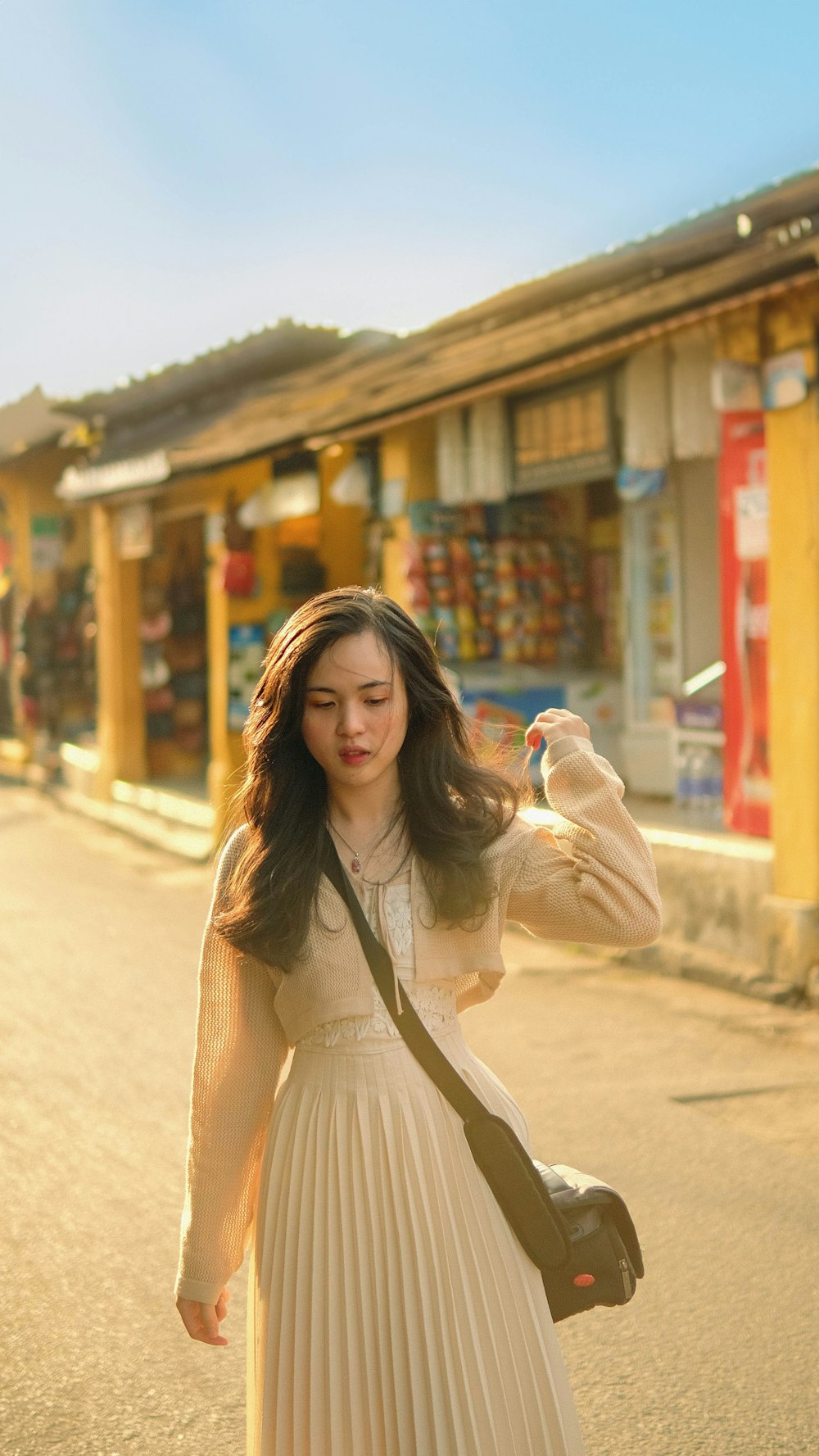 a woman in a white dress is walking down the street