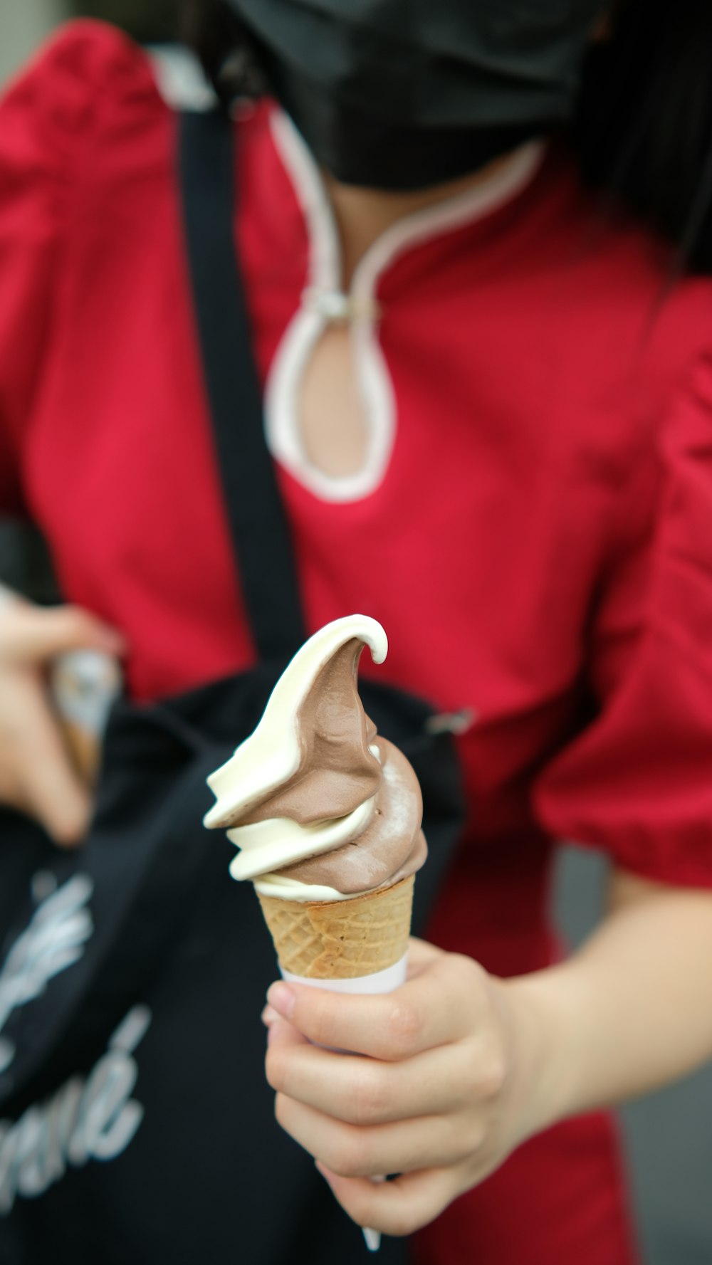 a woman in a red shirt is holding an ice cream cone